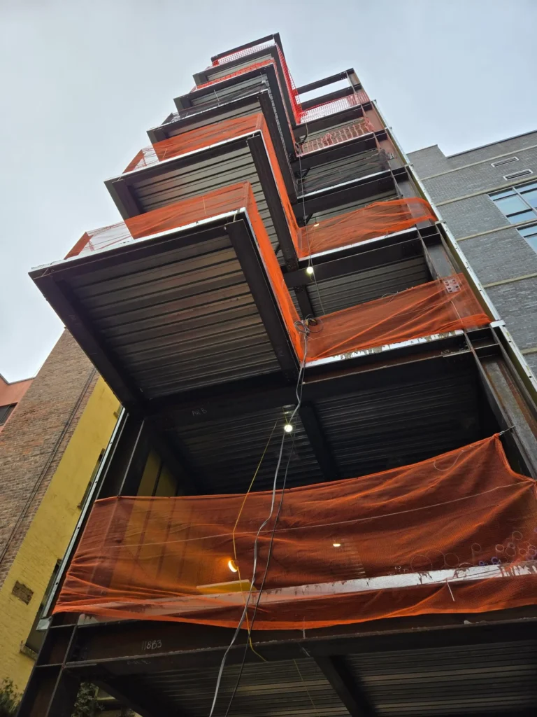 Building under construction with orange netting.