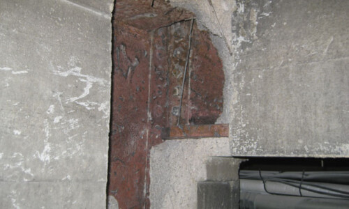 Damaged concrete wall with exposed rebar.