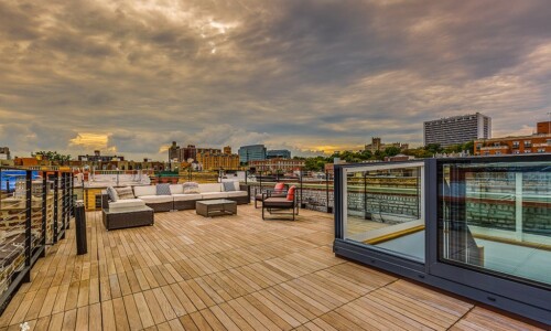 Rooftop terrace with cityscape and cloudy sky.