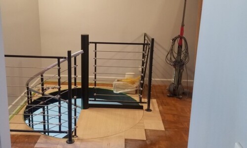 Staircase with wooden floor and cleaning supplies.