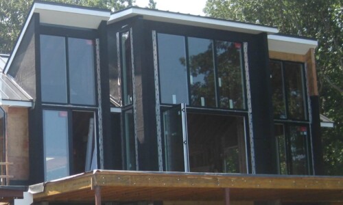 Modern house under construction with large windows.