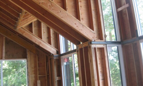 Wooden house framing with large windows.