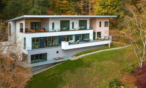 Modern hillside house surrounded by autumn trees.