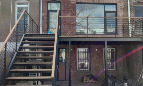 Brick building with balcony and exterior stairs.