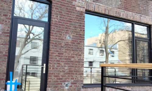 Brick building with large windows and balcony.
