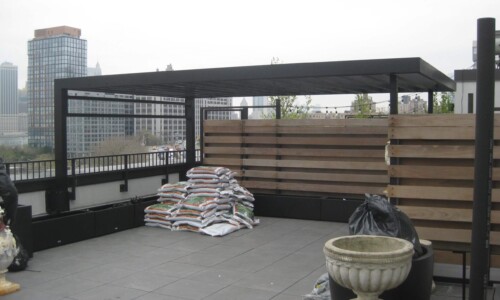 Rooftop patio with pergola and stacked materials.