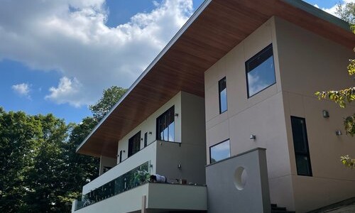 Modern hillside house under blue sky.