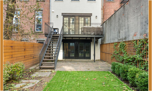 Backyard with green lawn and brick building.