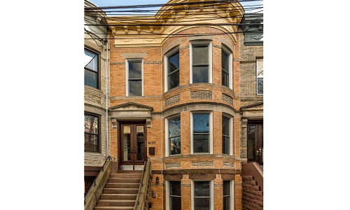 Historic brick townhouse with large bay windows.