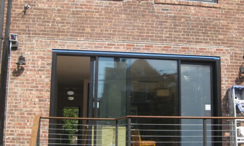 Brick house with large glass doors and windows.
