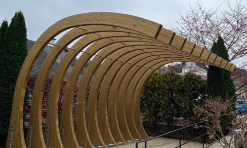 Wooden arch structure in a garden setting.
