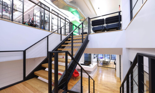 Modern open-plan office with wooden stairs.