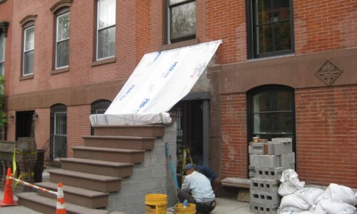 Construction work outside brick building entrance.